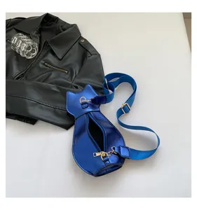 Detail view of a trendy metallic blue cat-shaped crossbody bag on a white surface.