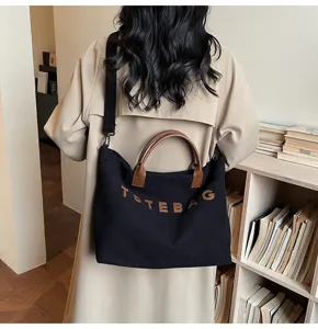 Minimalist black corduroy tote bag featuring brown handles, large capacity and stylish design.