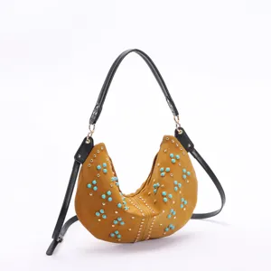 Detail of retro crescent hobo bag with turquoise beads and rivets in tan leather finish