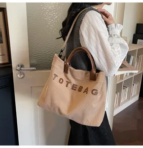Corduroy tote bag detail showing large capacity, brown handles and casual letter design.