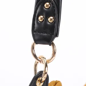 Macro detail of black leather bag strap with gold studs and shiny metal hardware rings