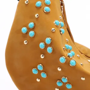 Close-up of retro crescent bag with turquoise studs and gold rivets