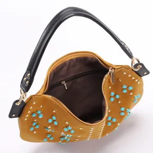 Detailed macro view of a retro crescent underarm bag with turquoise beads and studs