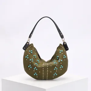 Detailed view of an olive green crescent bag with turquoise and gold rivet studs