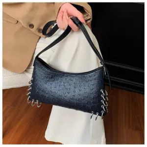 Close-up of the punk style black shoulder bag featuring metal rings and unique texture.