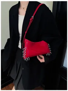 Detail shot of red glossy shoulder bag featuring edgy metal ring grommets and punk style.