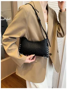Chic black ostrich-grain shoulder bag featuring metal ring details, trendy punk style.