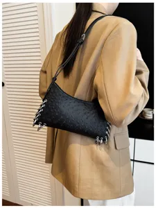 Detailed shot of a black punk style shoulder bag featuring metal rings and textured finish.