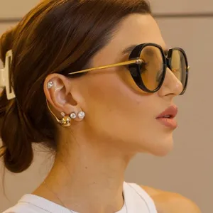 Vue de profil rapprochée de lunettes de soleil ovales oversize avec des branches dorées.