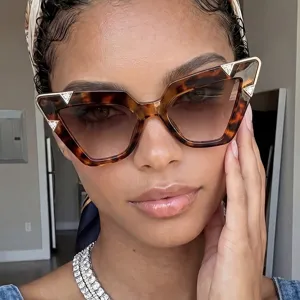 Macro view of tortoise-shell cat-eye sunglasses with rhinestone corner accents on model