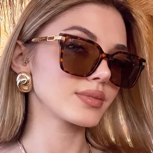 Close-up of model wearing vintage tortoise square sunglasses and gold swirl earrings