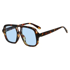 Lunettes de soleil carrées oversize à double pont avec monture écaille et verres bleu clair.