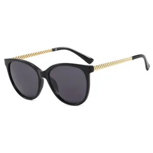 Lunettes de soleil œil-de-chat rétro chics pour femmes, montures noires mode et branches dorées.