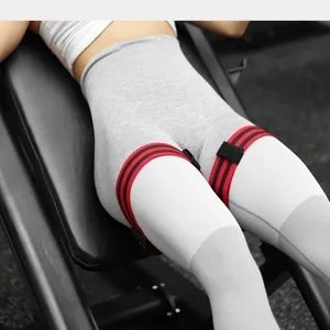 Detailansicht der rot-schwarzen BFR-Trainingsbänder an den Oberschenkeln im Fitnessstudio