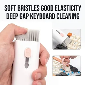 Close-up of keyboard cleaning kit including retractable soft brush and pink keycap puller tool.