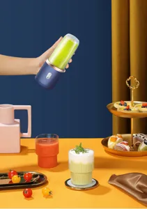Tragbarer blauer USB-Entsafter über einem bunten Obst- und Desserttisch gehalten