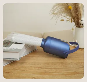 Close-up of a blue portable multi-functional dryer with dual flexible hoses on a wooden table
