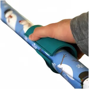 Detailansicht eines grünen Geschenkpapier-Schneiders auf Weihnachtsrollen
