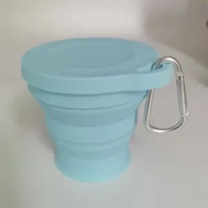 Tazza pieghevole in silicone azzurro con coperchio e moschettone in metallo argento.