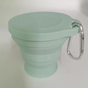 Primo piano di una tazza da viaggio pieghevole in silicone verde menta con moschettone