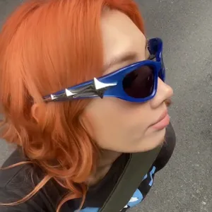 Primo piano di una modella che indossa occhiali da sole Y2K blu con dettaglio a stella