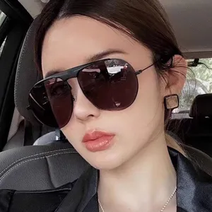 Primer plano de elegantes gafas de sol de aviador negras usadas por una modelo en un coche