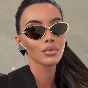 Gros plan de lunettes de soleil ovales rétro avec monture dorée sur un mannequin.