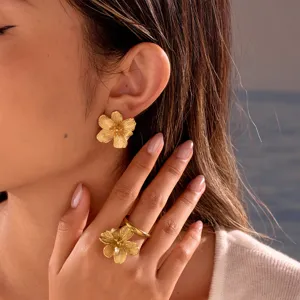 Close-up detail showing textured gold flower earrings and matching ring on model