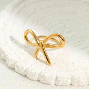 Nahaufnahme eines goldenen Edelstahl-Schleifenknotenrings auf einem weißen Sockel.