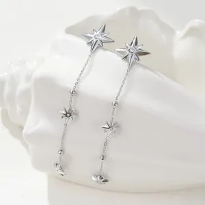 Close-up detail of silver stainless steel long tassel earrings with eight-pointed star motifs.