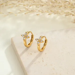 Macro detail of gold-plated stainless steel hoop earrings featuring clear CZ flower motifs