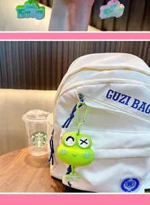 Nahaufnahme eines süßen grünen Silikon-Frosch-Schlüsselanhängers an einer weißen Tasche