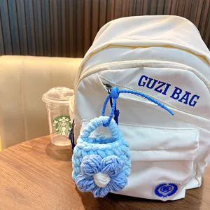 Lovely handmade blue woven flower coin purse keychain accessory on a white backpack