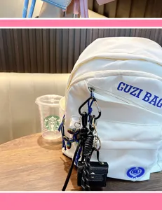 Detailed view of a black PU mini square bag keychain charm on a white backpack
