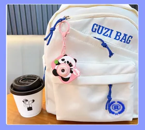 Cute panda-shaped projection camera keychain hanging on a white backpack detail view