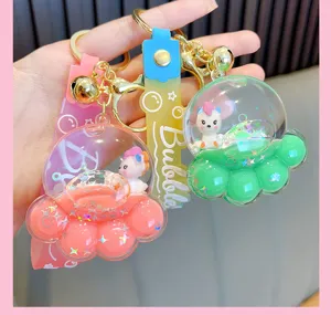 Close-up of cute unicorn cat paw liquid keychains with glitter and gold bell charms.