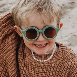 Primer plano de gafas de sol redondas verdes para niños con acabado mate y protección UV.