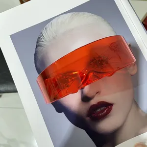 Close-up detail of orange futuristic visor sunglasses displayed on a fashion magazine.