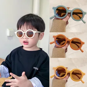 Toddler wearing white round frame sunglasses beside blue, orange and yellow color options