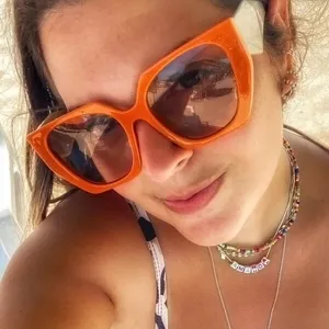 Κοντινό πλάνο μοντέρνων ακανόνιστων πορτοκαλί γυαλιών ηλίου που φοράει μια γυναίκα έξω