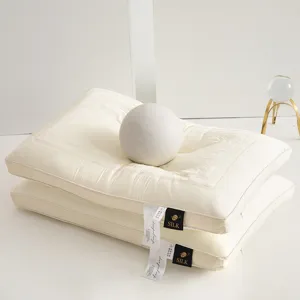 Detailed shot of two stacked cream tencel latex pillows with decorative embroidery