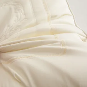 Close-up view of elegant embroidery detail and smooth Tencel fabric on a latex pillow.