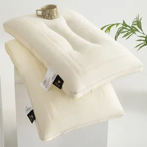 Two stacked cream latex pillows featuring elegant embroidery and silk fabric labels