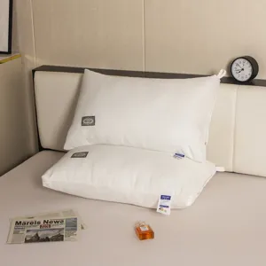 Juego de dos almohadas de hotel blancas con textura de trenza en una cama acogedora