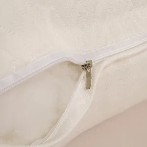 Detalle de una almohada de hotel blanca con textura, cremallera y relleno de fibra suave