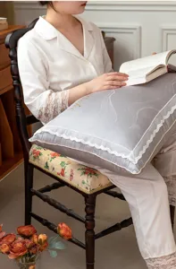 Close-up of a luxurious grey pillow featuring intricate lace borders in a home scene