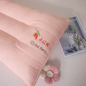 Close-up of pink neck protection pillow with embroidered goji berry design