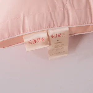 Close-up detail of brand and quality tags on a soft pink 48x74cm cervical pillow