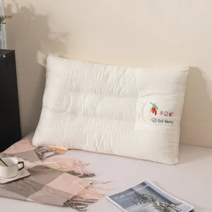 Close-up detail of white quilted pillow with delicate goji berry embroidery and soft texture