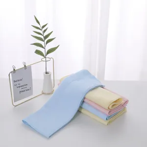 Stack of soft pastel latex face towels on a white table with decorative plant detail